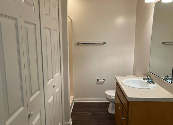 A bathroom with a toilet, sink, and mirror.