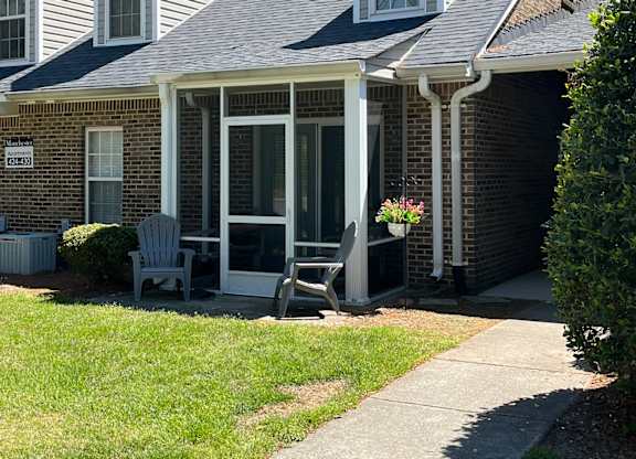 A house with a grey roof and a porch with a chair.