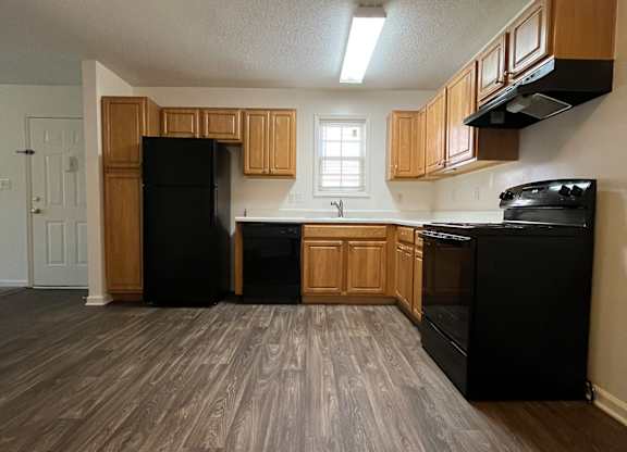 A kitchen with black appliances and wooden cabinets.