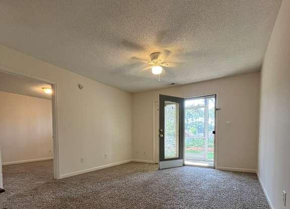 A room with a carpeted floor and a ceiling fan.