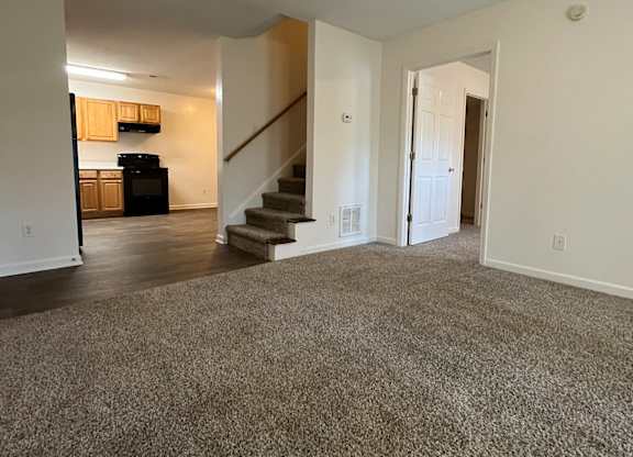 A spacious living room with a staircase leading to the upper floor.