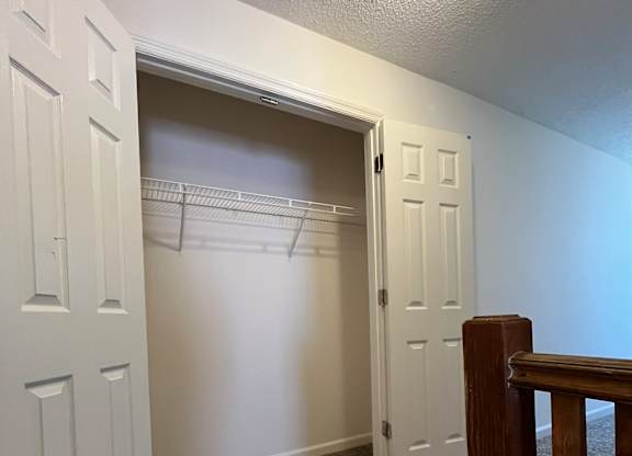 A white door is open to a hallway with a carpeted floor.