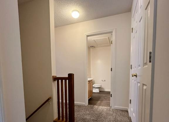 A hallway with a carpeted floor and white walls.