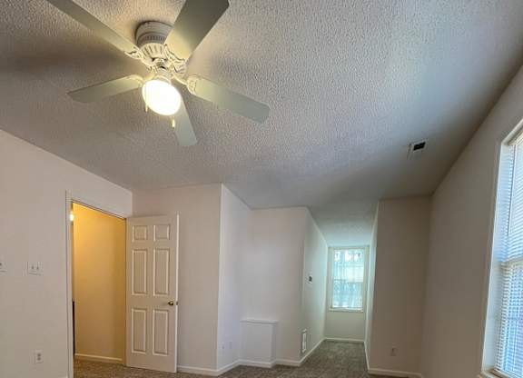 A room with a ceiling fan and carpeted floor.