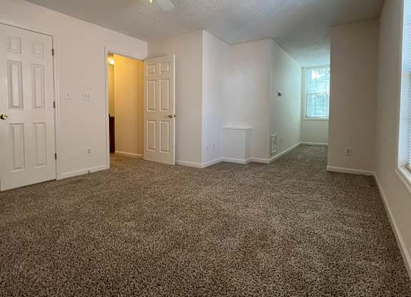 A room with a ceiling fan and carpeted floor.