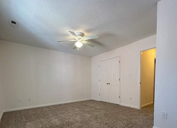 A room with a ceiling fan and carpeted floor.