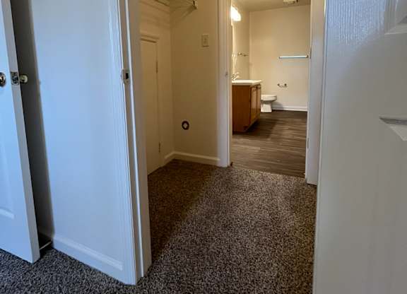 A hallway with a carpeted floor and white walls.