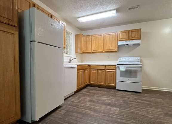 A kitchen with a white refrigerator and a white dishwasher.