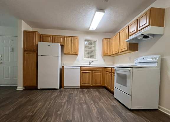 A kitchen with white appliances and wooden cabinets.