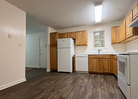 A kitchen with white appliances and wooden cabinets.