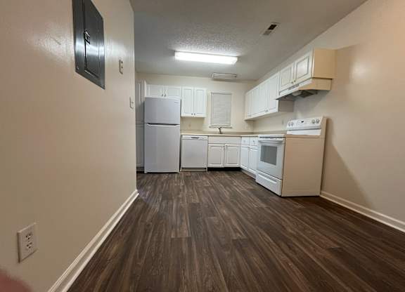 A kitchen with white cabinets and a refrigerator.