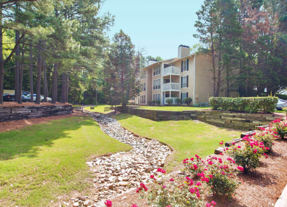 Community with building, rock bed, flowers and woods at Laurel Oaks, North Carolina