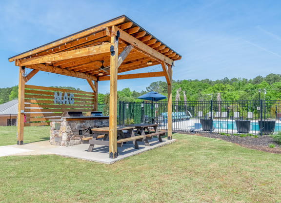 a picnic table under a wooden pavilion next to a swimming pool at Carmel Vista, McDonough, Georgia