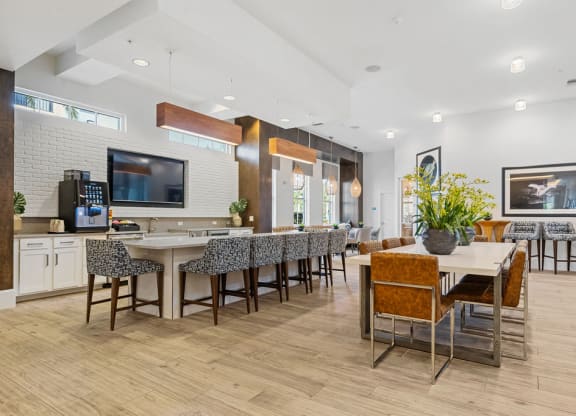 The clubhouse demonstration kitchen and large dining table flanked by bar height chairs with pub tables at Inspira, Naples, 34113