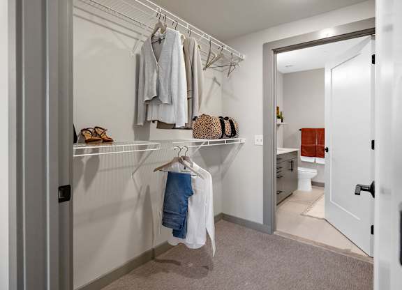 a walk in closet in a bedroom with a door to the bathroom