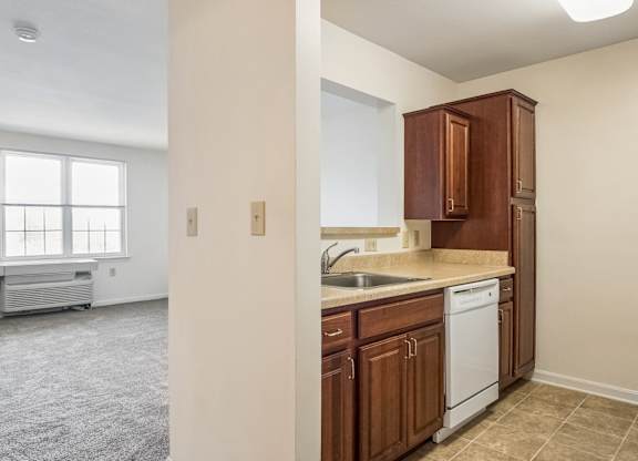 A kitchen with brown cabinets and a white dishwasher.