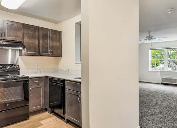 A kitchen with dark brown cabinets and a stainless steel oven.