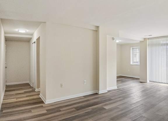 A spacious room with wooden flooring and white walls.