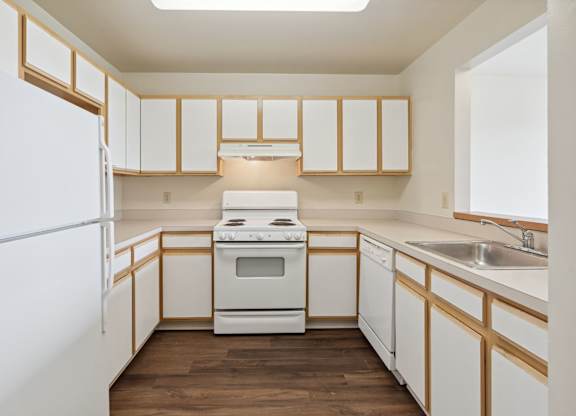A kitchen with white appliances and wooden cabinets.