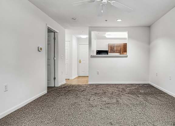 A room with a carpet floor and a ceiling fan.