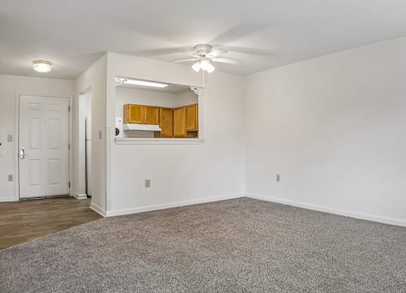A room with a white ceiling and walls, a grey carpet, and a white door.