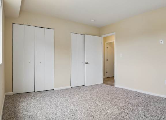Three white doors are in a room with carpeted floor.