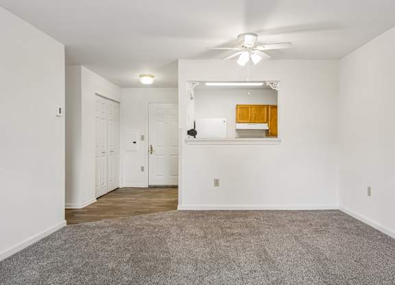 A spacious room with a ceiling fan and carpeted floor.