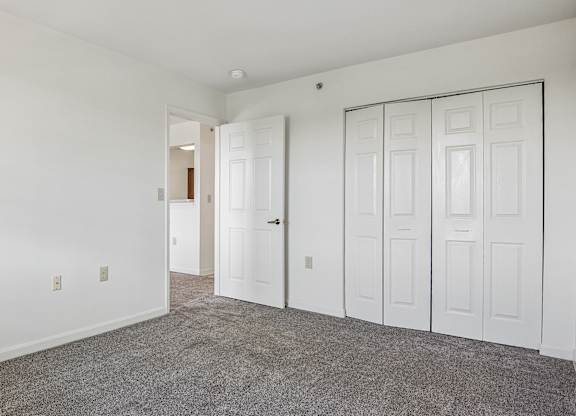 A room with white walls and a grey carpet.