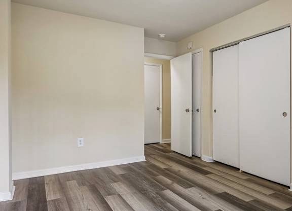 A room with three white doors and a wooden floor.