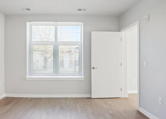 A room with a white door and a window with blinds.