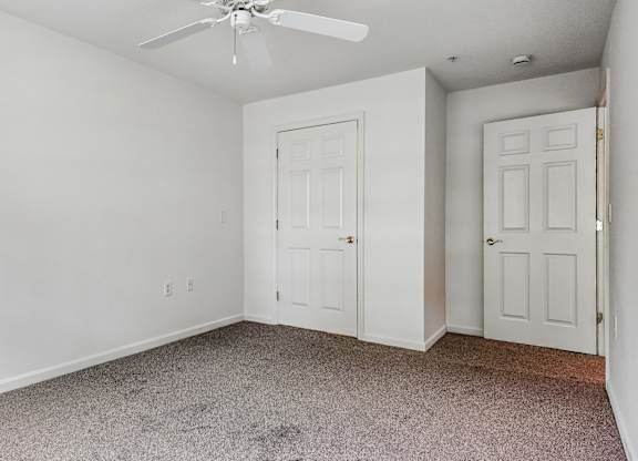 A room with a ceiling fan and two doors.