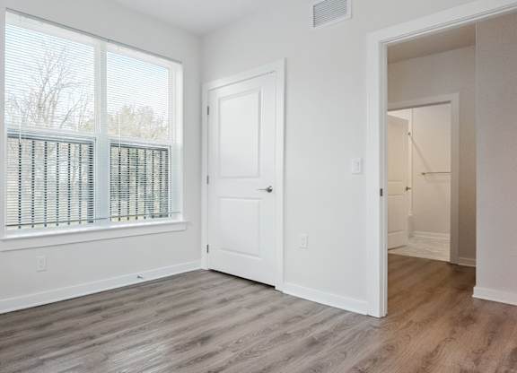 A room with a white door and a window with blinds.