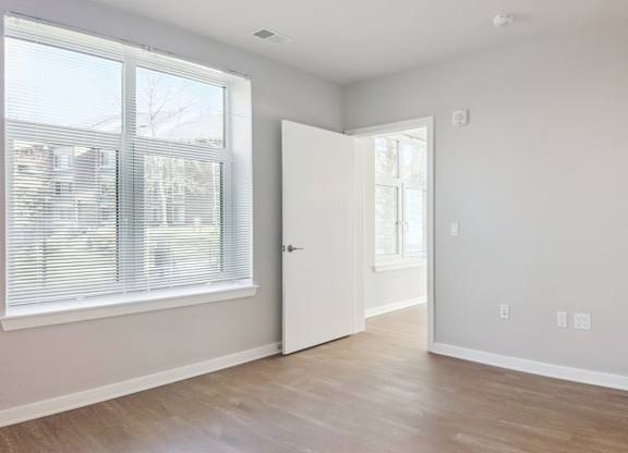 A room with a white door and a window with blinds.