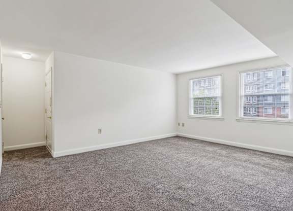 Living room in Towson senior apartment with two windows and neutral carpet