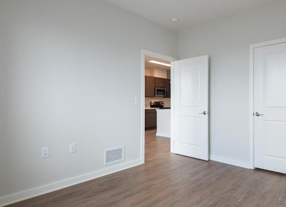 A room with two doors and a hallway leading to another room.