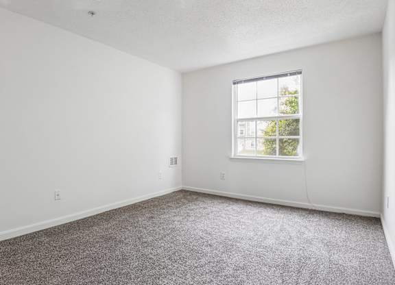 A room with a carpeted floor and a window.