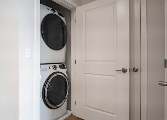 A white washing machine is in a white doorway.