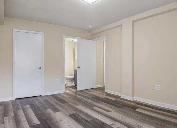 A room with wood flooring and two white doors.