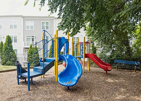 A playground with a blue slide and a red slide.
