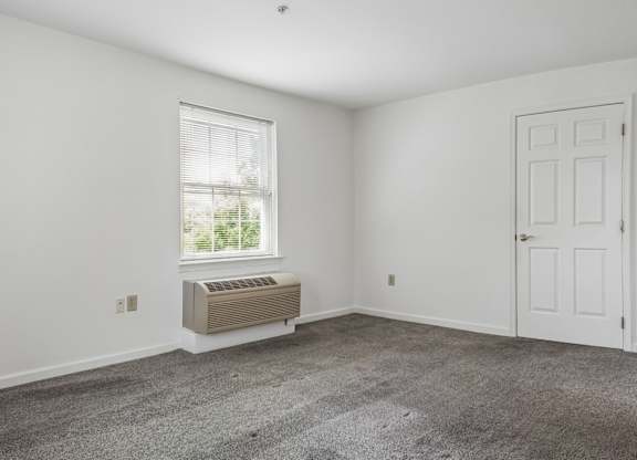 A room with a window, air conditioner, and two doors.