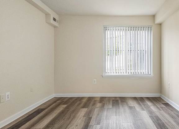 A room with a window and wooden flooring.
