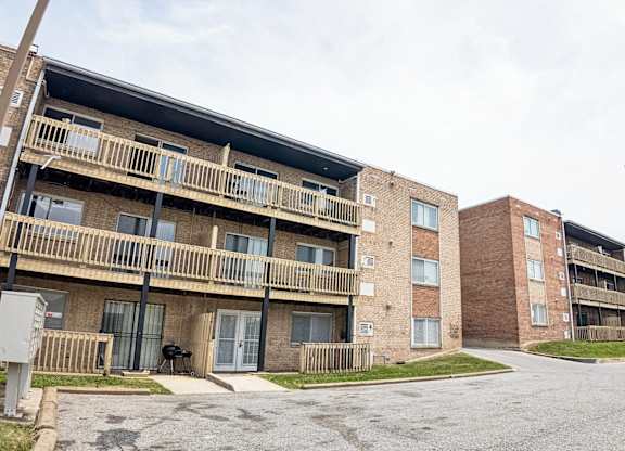Apartment complex with brick buildings and a parking lot in front.