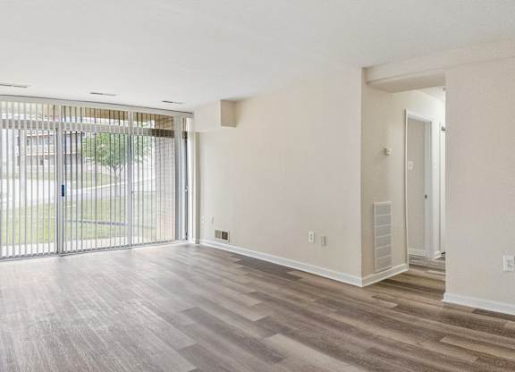 A room with a sliding glass door and wooden flooring.