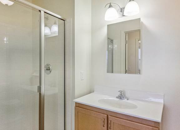 A bathroom with a sink, mirror, and shower.