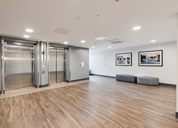 A hallway with wood floors and two elevators.