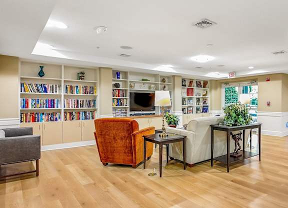 A living room with a wooden floor and a bookshelf filled with books.