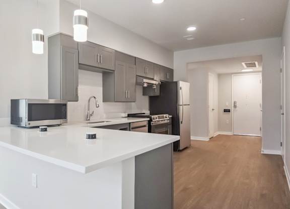 A kitchen with a white countertop and grey cabinets.