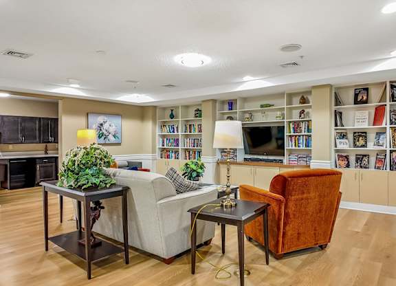 A living room with a fireplace, a couch, a chair, and a bookshelf filled with books.