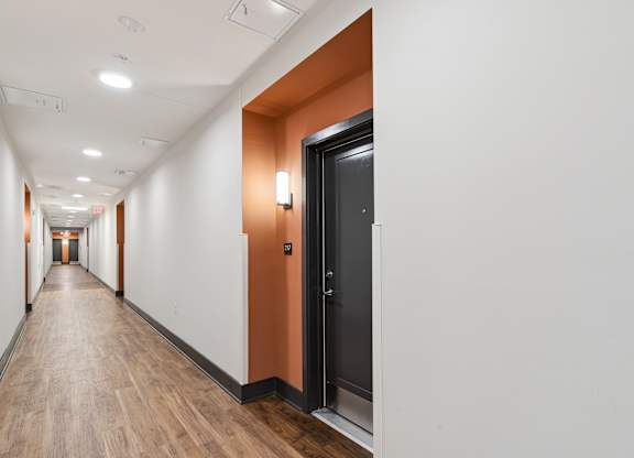 A long hallway with a black door on the right.