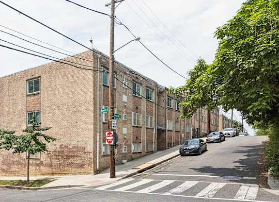 A street view with a building on the left and cars parked on the right.